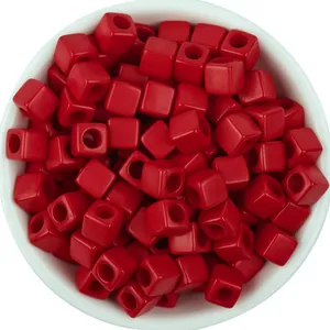 Detailed view of vibrant red square acrylic beads in a white bowl, perfect for DIY jewelry making.