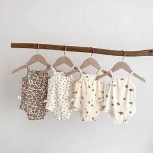 Detailed view of cute floral and fruit print baby sleeveless rompers hanging on a wooden rod.