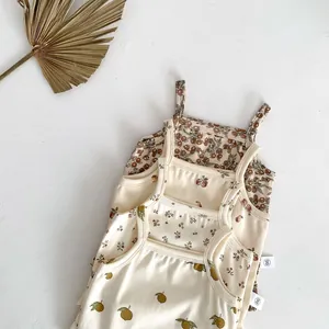 Detailed shot of cute baby summer camisole rompers with playful fruit and floral prints.
