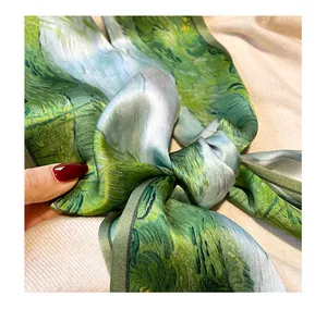 Close-up detail of green silk scarf, showing smooth texture, artistic print and elegant knot.