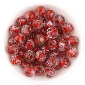 Close-up detail of faceted red glass beads with rose pattern and gold glitter, DIY accessory.