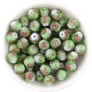 Close-up detail of faceted green glass beads with gold foil rose pattern for DIY jewelry making.
