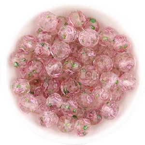 Closeup of pink faceted glass beads with rose pattern and sparkling gold sand for DIY crafts.