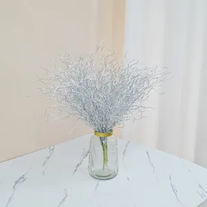 Close-up of artificial silver curly willow branches arranged in elegant glass vase