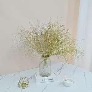 Elegant gold and silver curly decorative branches in a glass vase on a tabletop