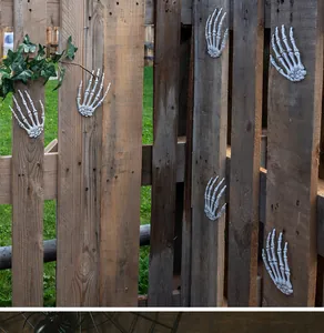 Realistic Halloween skeleton hand props attached to a rustic wooden fence decoration.