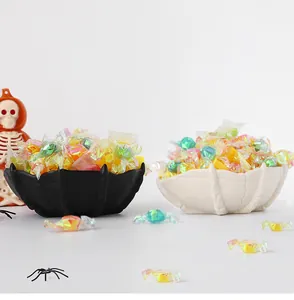 Close-up view of black and white skeleton hand bowls filled with colorful candies for Halloween