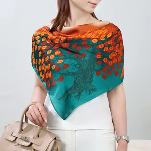 Silk scarf detail showing vibrant orange and green autumn tree print draped elegantly on model.