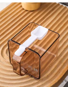 Detailed view of a transparent amber seasoning jar with a white plastic spoon