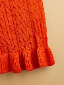 Close-up detail of soft orange cable knit pet sweater for small dogs with cute ruffle hem.