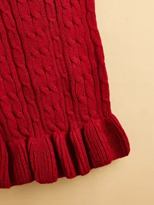 Close-up detail of red cable knit dog sweater with cute ruffled hem, soft texture.