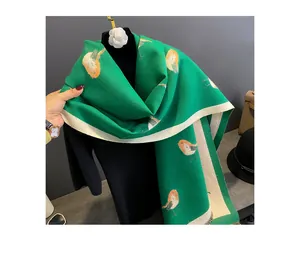 Green cashmere feel winter scarf detail featuring elegant bird print and contrast white trim.
