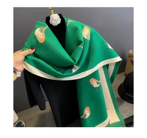 Green cashmere-feel scarf detail, bird print pattern, elegant draped shawl closeup.