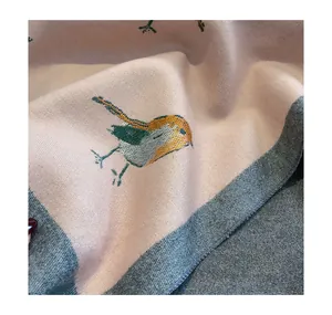 Close-up detail of soft cashmere-feel winter scarf featuring delicate embroidered bird pattern.