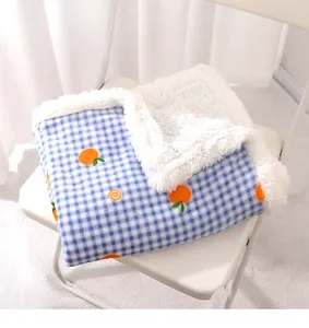 Detailansicht der flauschigen Haustierdecke, blaues Karomuster mit süßer Orangestickerei.