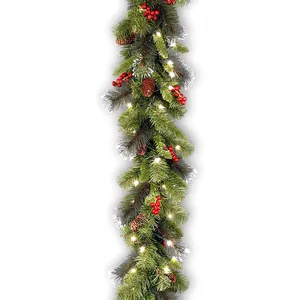 Close-up of a festive Christmas pine garland with warm lights, pine cones and red berries