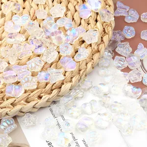 Detailansicht von schillernden Glasperlen in Schmetterlings- und Blumenform für DIY-Schmuck.
