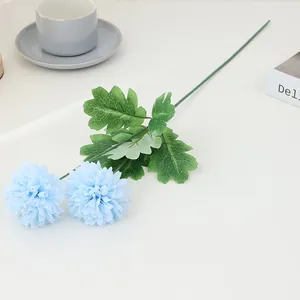 Detailed view of artificial blue pompon chrysanthemum flower branch with green leaves.