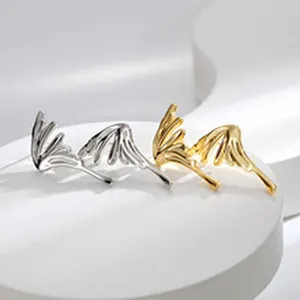 Dettaglio di orecchini in acciaio inossidabile oro e argento a forma di ala su base bianca.