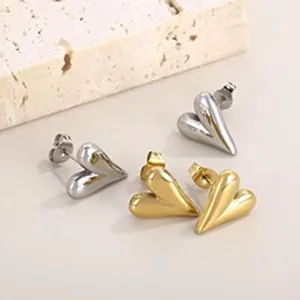 Dettaglio ravvicinato di orecchini a lobo a forma di cuore in acciaio inox oro e argento