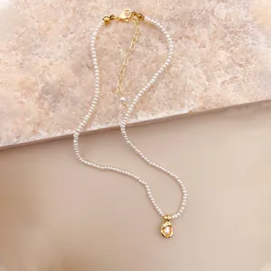 Detailaufnahme einer eleganten Süßwasserperlenkette mit einem unregelmäßigen Goldanhänger