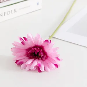 Primo piano della testa del fiore di gerbera artificiale rosa sui dettagli del tavolo.