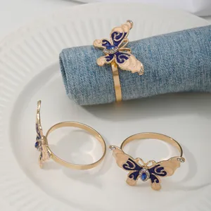 Gold-tone butterfly napkin rings with blue enamel and rhinestones for dining table decor.