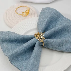 Golden metal lotus napkin ring detail shot, elegant table setting accessory for western dinner.