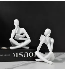 Figuras abstractas de pensadores en resina blanca leyendo sobre libros decorativos