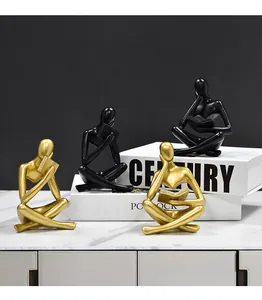 Vista detallada de estatuas de pensadores abstractos en oro y negro sobre libros decorativos