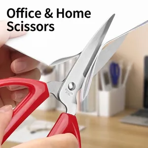 Red handle stainless steel household scissors cutting paper detail macro view