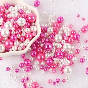 Primo piano di perle sintetiche rosa e bianche di varie misure per decorazioni fai da te.