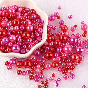 Vista di dettaglio di perle rosse e rosa di varie dimensioni su sfondo soffice bianco