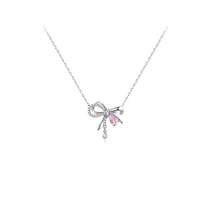 Detalle de cerca del collar con colgante de lazo brillante con cristal rosa y cadena de plata.
