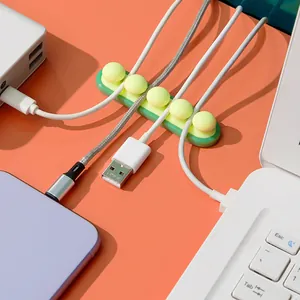 Bright green silicone desktop cable organizer holding various charging cords on an orange desk
