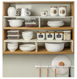 Expandable white kitchen cabinet shelf organizer for tiered storage of ceramic bowls and jars