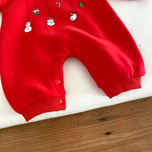 Détail de grenouillère polaire rouge pour bébé avec motif de Noël et boutons-pression.
