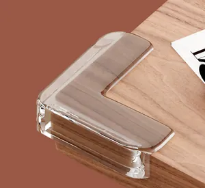 Close-up detail of a transparent soft silicone L-shaped corner protector on wooden table edge