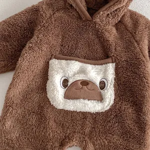 Close-up detail of soft brown fleece baby jumpsuit with cute cartoon animal pocket, warm hood.