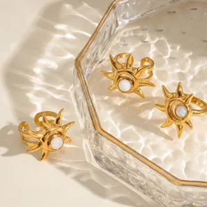 Detailansicht von sonnenförmigen goldenen Edelstahlringen mit weißen Steinen auf einem Tablett