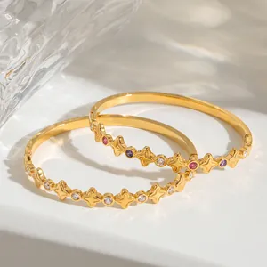 Detailansicht der 18k vergoldeten Armreifen mit Sternen und bunten Zirkonia-Steinen.