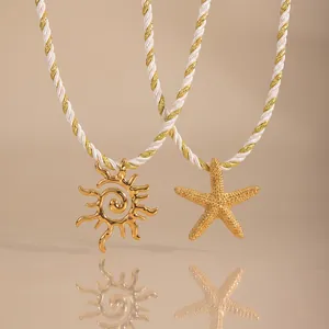 Detailaufnahme von goldenen Seestern- und Sonnenanhängern mit weiß-goldenen Ketten