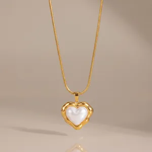 Primer plano de un collar con colgante de corazón dorado e incrustación de perla