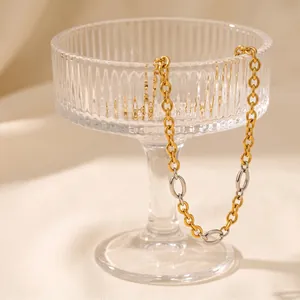 Detailed view of a mixed metal 18k gold plated stainless steel necklace on glass stand