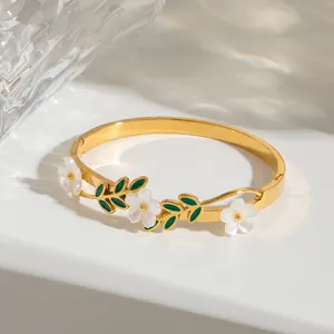 Makroansicht des 18k vergoldeten Armreifs mit weißen Blumenanhängern und Blättern