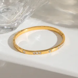 Detail of a minimalist 18k gold plated stainless steel bangle with inlaid zirconia.