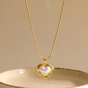Primer plano de un colgante de corazón con perla en una cadena de oro elegante