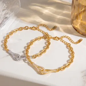 Detailaufnahme der ineinandergreifenden, mit Strass besetzten Anhänger an Goldarmbändern