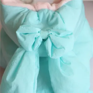 Detailed view of light blue dog winter coat featuring a cute bow and warm pink fleece