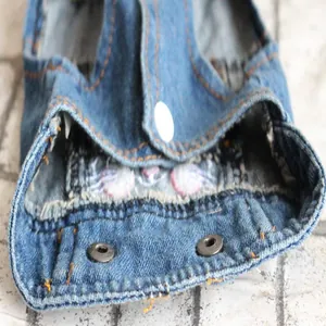 Macro view of blue denim pet vest featuring detailed rabbit embroidery and metal snaps